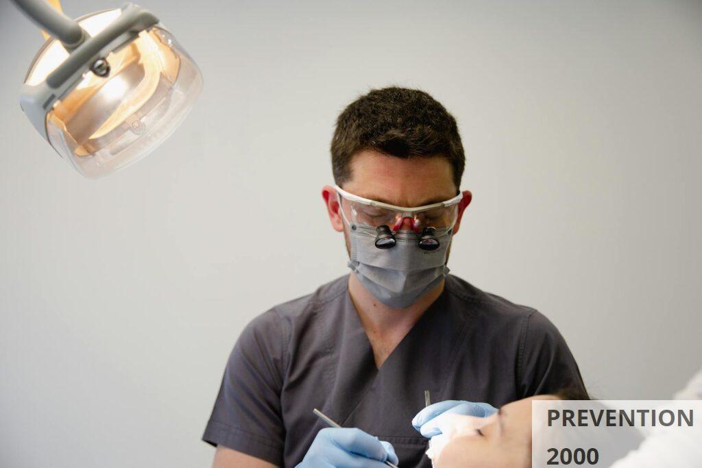 A dentist uses professional tools to treat a patient in a well-lit dental office.