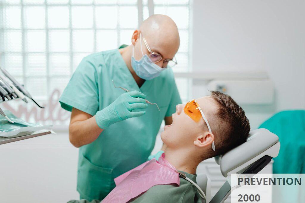 A dentist wearing gloves examines a patient sitting in a dental chair, focusing on oral health.